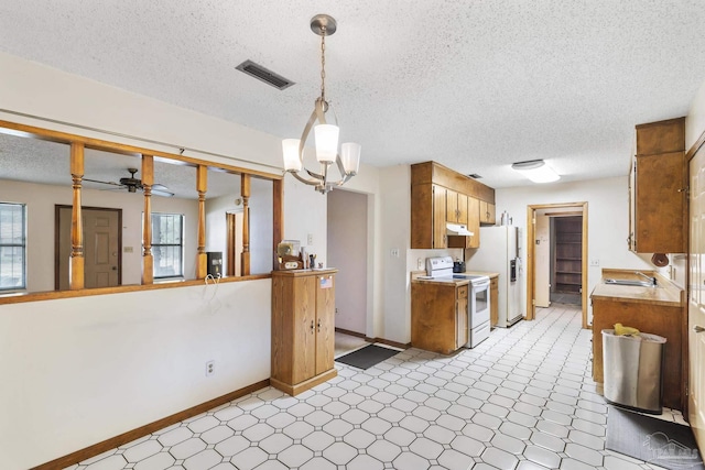 921 Candlestick Dr, Pensacola, FL 32514 - kitchen with white appliances, light countertops, a textured ceiling, under cabinet range hood, and brown cabinets