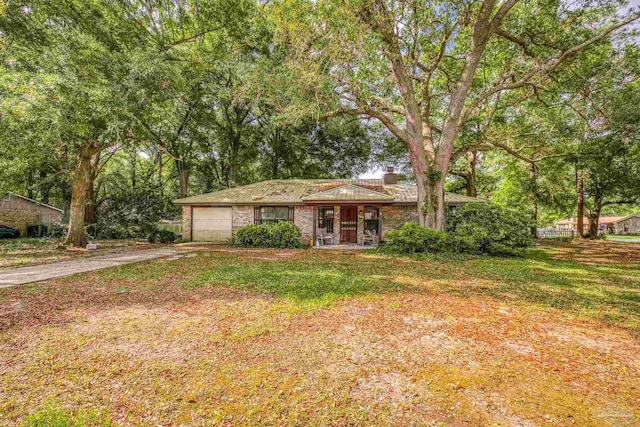 921 Candlestick Dr, Pensacola, FL 32514 - view of front of house with concrete driveway, a garage, a chimney, brick siding, and view of wooded area