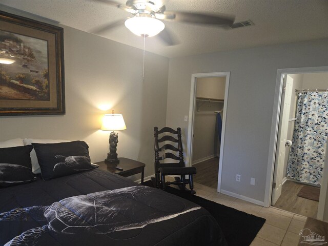 5358 Jenny Cir, Pace, FL 32571 - bedroom with light tile patterned floors, a walk in closet, a textured ceiling, ensuite bath, and a ceiling fan
