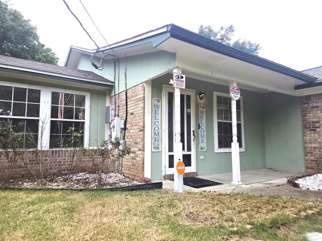 5358 Jenny Cir, Pace, FL 32571 - doorway to property with brick siding, covered porch, and a yard