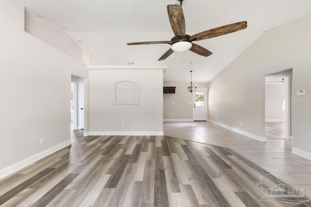 9317 Alekai Dr, Pensacola, FL 32526 - unfurnished living room with vaulted ceiling, a ceiling fan, wood finished floors, and a chandelier
