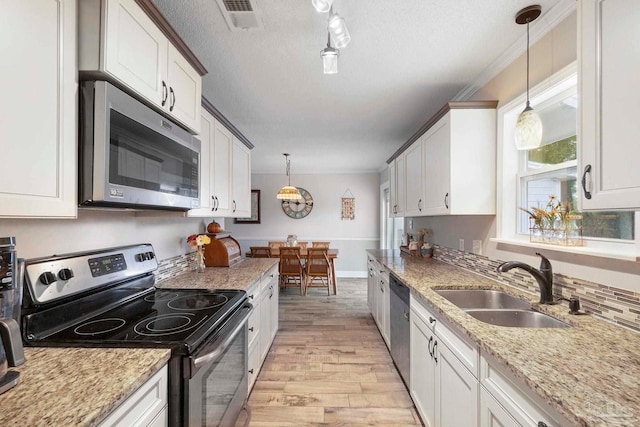 8150 Northpointe Blvd, Pensacola, FL 32514 - kitchen featuring stainless steel appliances, a sink, light wood-style floors, pendant lighting, and a textured ceiling