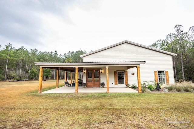 rear view of property with a lawn, a patio, and french doors