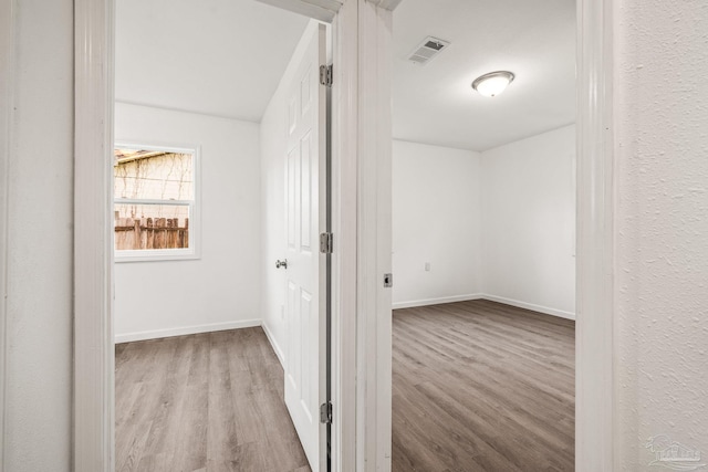 hallway with visible vents, wood finished floors, and baseboards