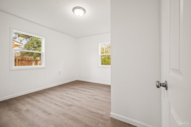 unfurnished room featuring a healthy amount of sunlight, baseboards, and wood finished floors