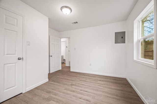 unfurnished bedroom with light wood-style flooring, electric panel, baseboards, and visible vents