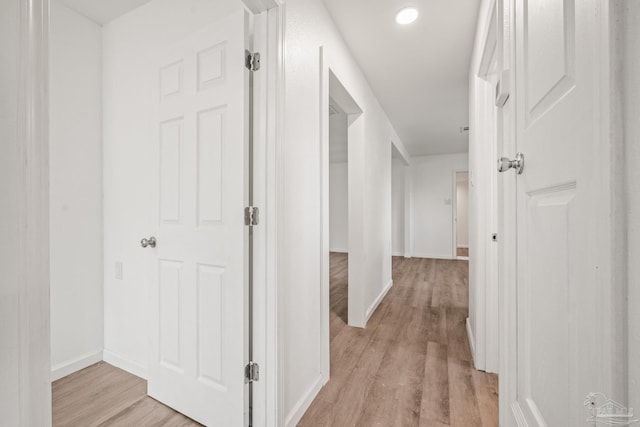 corridor featuring light wood-style flooring and baseboards