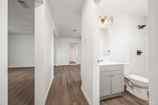 bathroom with vanity, wood finished floors, visible vents, a marble finish shower, and toilet