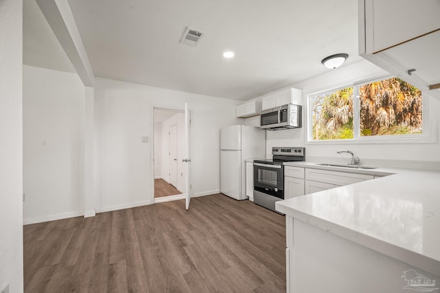 kitchen with visible vents, a sink, wood finished floors, appliances with stainless steel finishes, and light countertops