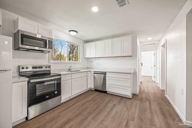 kitchen featuring visible vents, white cabinetry, stainless steel appliances, and a sink