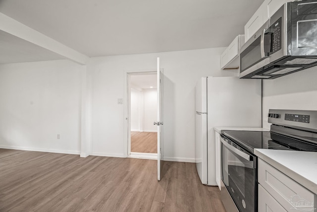 kitchen featuring light wood-type flooring, stainless steel appliances, white cabinets, light countertops, and baseboards