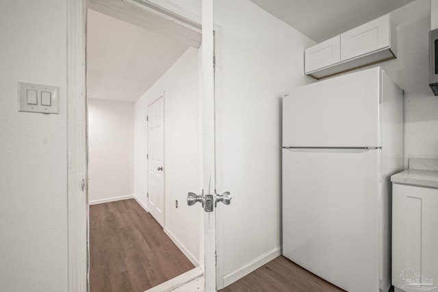 kitchen featuring wood finished floors, baseboards, freestanding refrigerator, light countertops, and white cabinetry