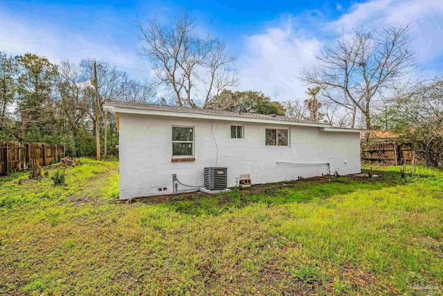 rear view of property with crawl space, a lawn, central AC, and fence