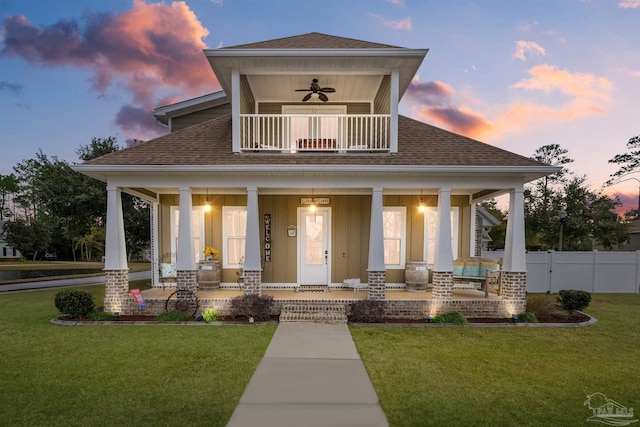 view of front of house featuring covered porch, a balcony, ceiling fan, and a yard