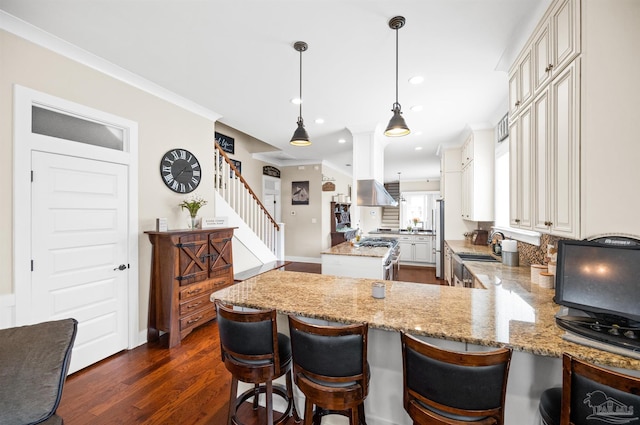 kitchen featuring decorative light fixtures, dark wood-type flooring, kitchen peninsula, a breakfast bar, and appliances with stainless steel finishes