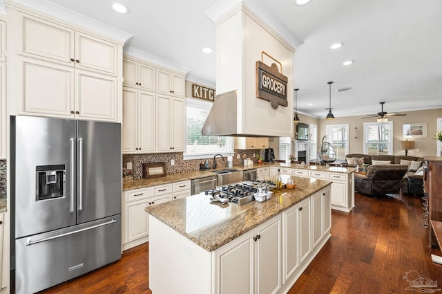 kitchen with appliances with stainless steel finishes, ceiling fan, stone countertops, a kitchen island, and dark wood-type flooring