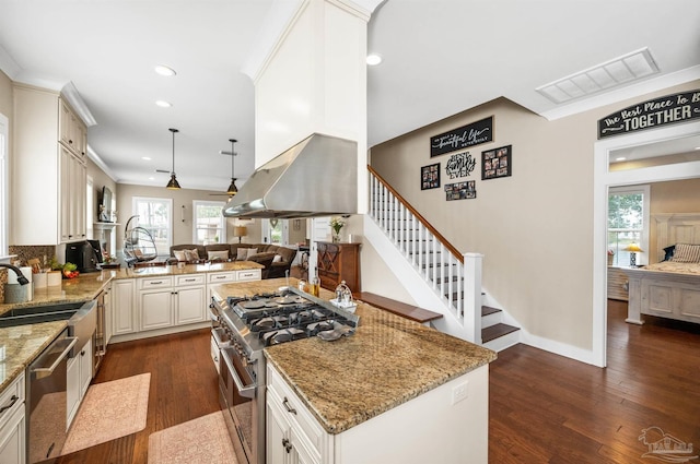 kitchen featuring island exhaust hood, stainless steel appliances, kitchen peninsula, pendant lighting, and dark hardwood / wood-style floors