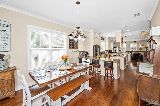 dining room featuring ceiling fan with notable chandelier, crown molding, and dark wood-type flooring