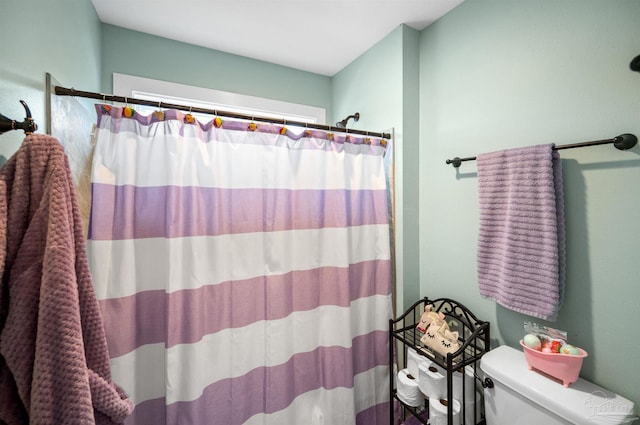 bathroom featuring toilet and curtained shower