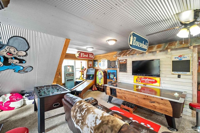 rec room featuring wood walls, ceiling fan, and light colored carpet