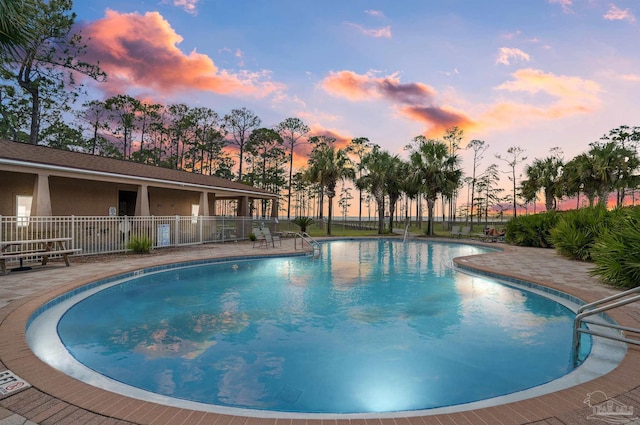 pool at dusk with a patio area