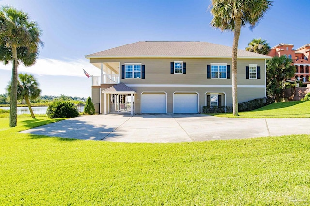 view of front of home featuring concrete driveway, a water view, an attached garage, and a front lawn