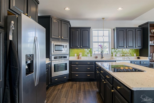 kitchen featuring decorative backsplash, dark wood-style flooring, decorative light fixtures, appliances with stainless steel finishes, and light stone countertops