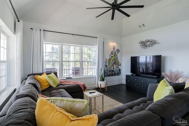 living area featuring dark wood-style flooring, vaulted ceiling, a healthy amount of sunlight, and visible vents