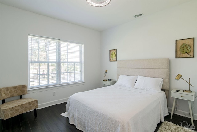 bedroom with visible vents, baseboards, and wood finished floors