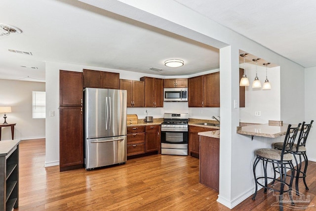 4662 Oakland Dr, Pensacola, FL 32526 - kitchen with stainless steel appliances, wood finished floors, a kitchen breakfast bar, and light countertops