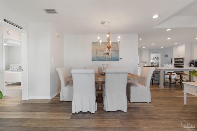 dining area featuring dark hardwood / wood-style flooring and an inviting chandelier