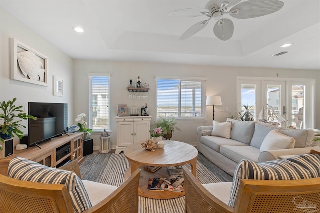 living room featuring a raised ceiling and ceiling fan