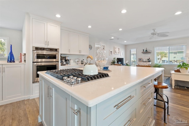 kitchen with white cabinetry, a breakfast bar area, a center island, stainless steel appliances, and light wood-type flooring