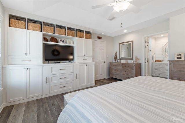 bedroom featuring a raised ceiling, ceiling fan, dark hardwood / wood-style floors, and ensuite bath