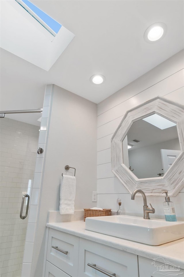 bathroom with a skylight, vanity, and walk in shower