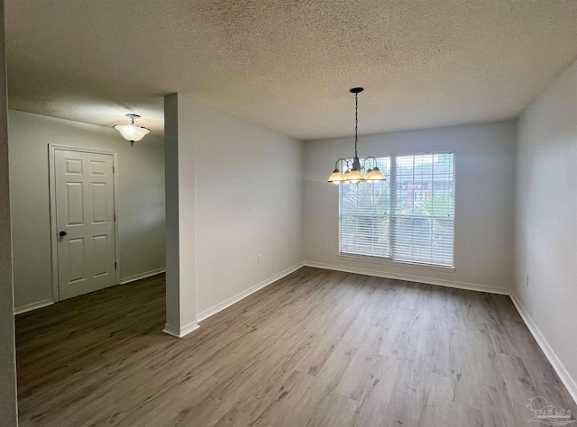 4888 La Casa Cir, Pace, FL 32571 - unfurnished dining area with wood finished floors, a textured ceiling, a chandelier, and baseboards