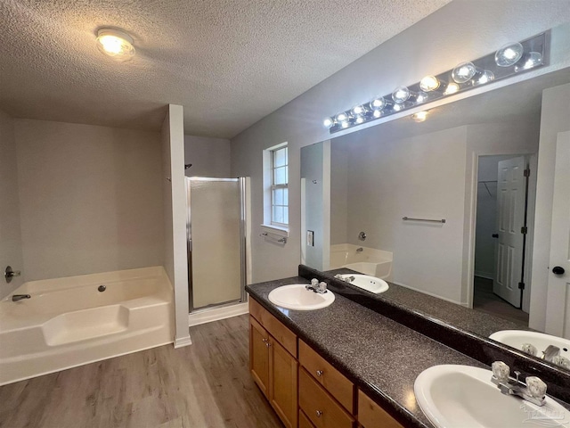 4888 La Casa Cir, Pace, FL 32571 - bathroom featuring a textured ceiling, wood finished floors, a garden tub, a shower stall, and double vanity