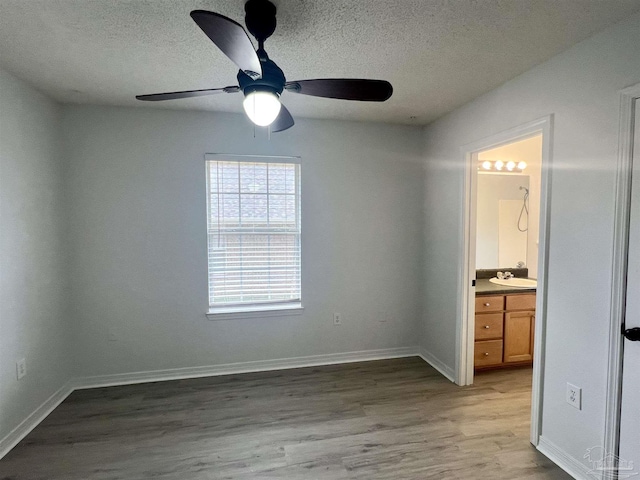 4888 La Casa Cir, Pace, FL 32571 - unfurnished bedroom featuring light wood-style flooring, a textured ceiling, baseboards, ensuite bath, and a ceiling fan