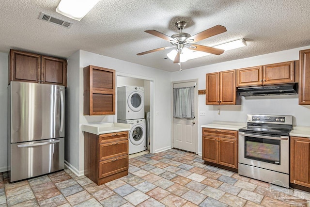 10449 Bernice Rd, Milton, FL 32583 - kitchen featuring stainless steel appliances, under cabinet range hood, stacked washer and clothes dryer, light stone finish floors, and baseboards