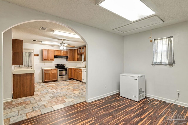 10449 Bernice Rd, Milton, FL 32583 - kitchen with white appliances, under cabinet range hood, a sink, a textured ceiling, and arched walkways