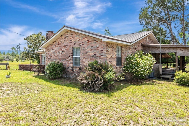 10449 Bernice Rd, Milton, FL 32583 - view of home's exterior with a chimney, a yard, brick siding, and metal roof