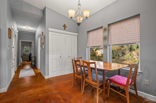 dining space with a healthy amount of sunlight, baseboards, concrete floors, and a notable chandelier