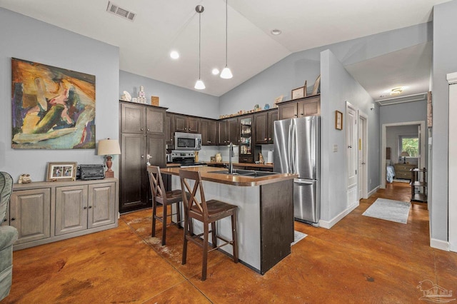 kitchen with dark brown cabinetry, visible vents, appliances with stainless steel finishes, a center island with sink, and lofted ceiling