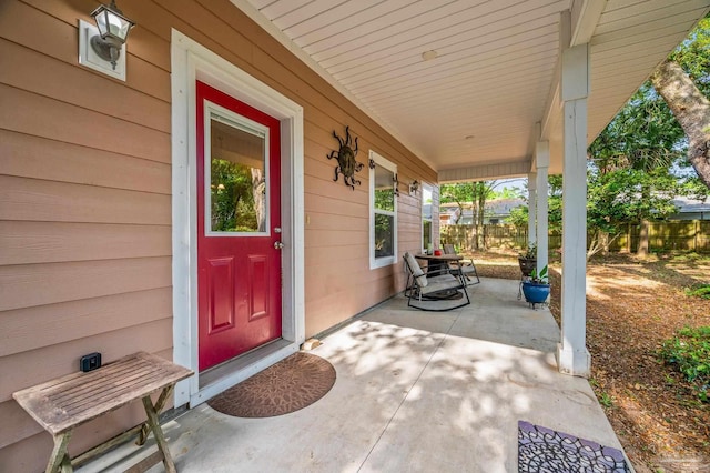 entrance to property featuring covered porch and fence