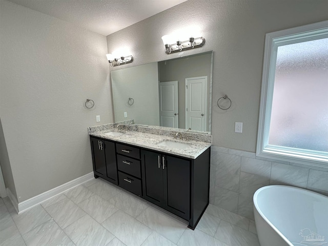 bathroom featuring tile walls, a healthy amount of sunlight, vanity, and a tub