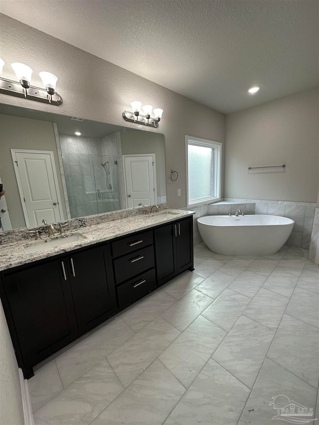 bathroom featuring tile walls, a textured ceiling, vanity, and separate shower and tub