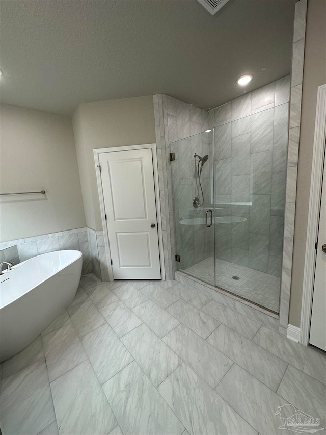 bathroom featuring plus walk in shower, tile walls, and a textured ceiling