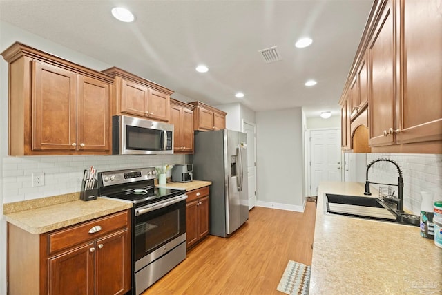 kitchen featuring tasteful backsplash, sink, light hardwood / wood-style floors, and stainless steel appliances