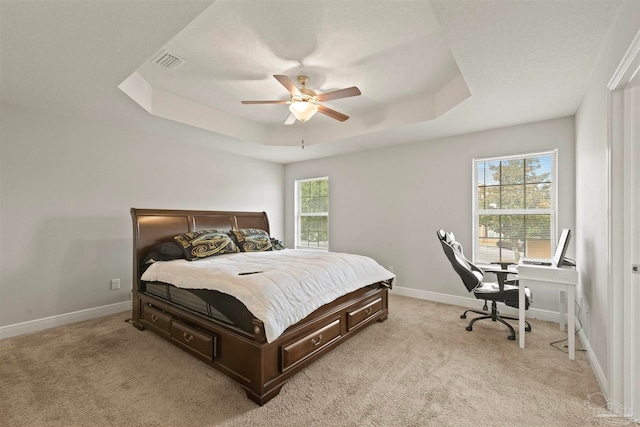 carpeted bedroom with ceiling fan and a raised ceiling