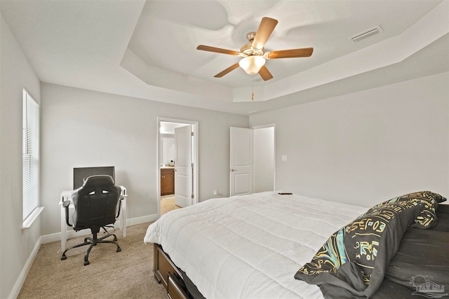 carpeted bedroom featuring ceiling fan, connected bathroom, and a tray ceiling